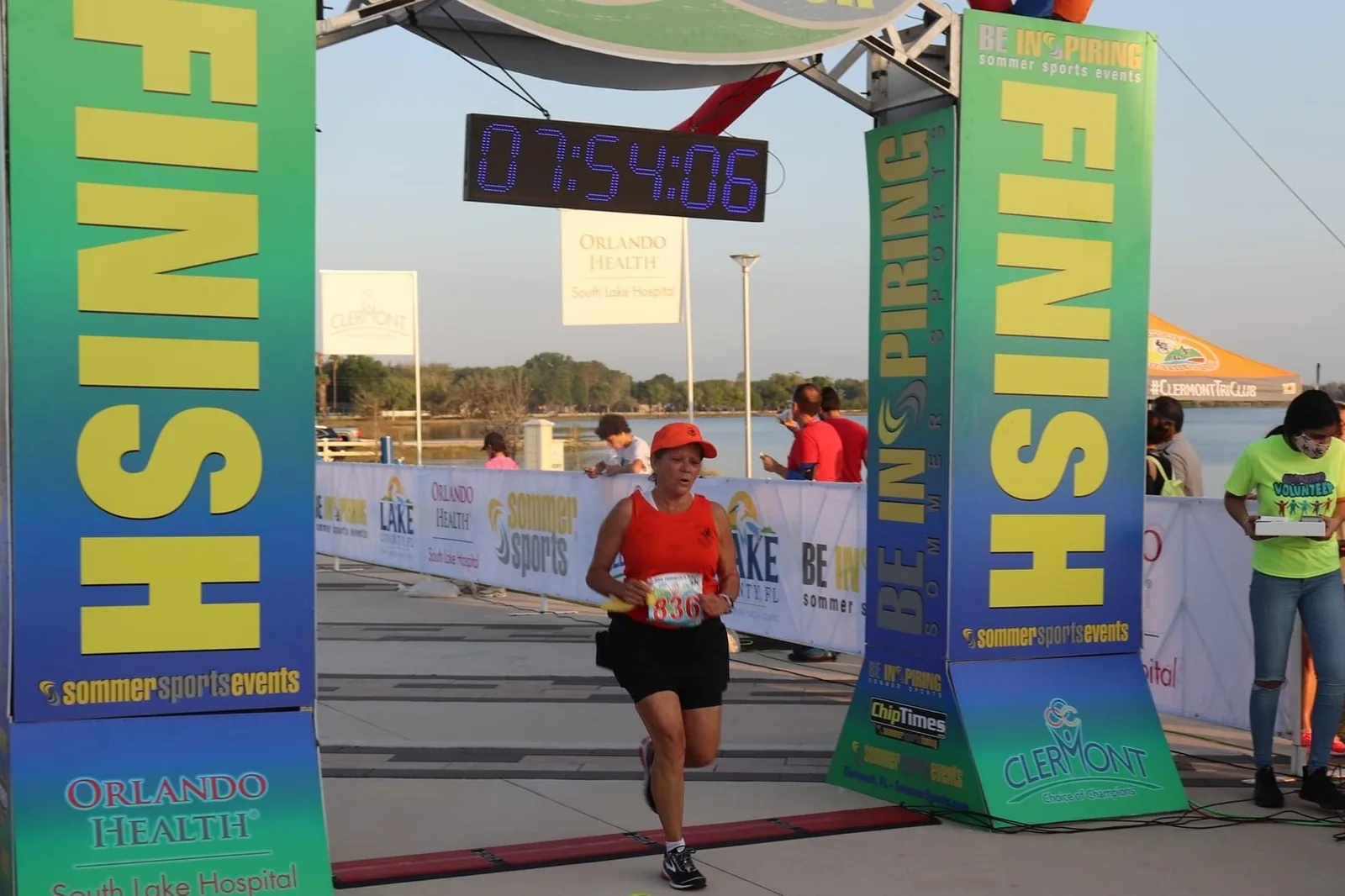 A runner crosses the finish line of a 5K at Victory Pointe, the lakefront park where the Enchanted Forest of Trees stands each holiday season.