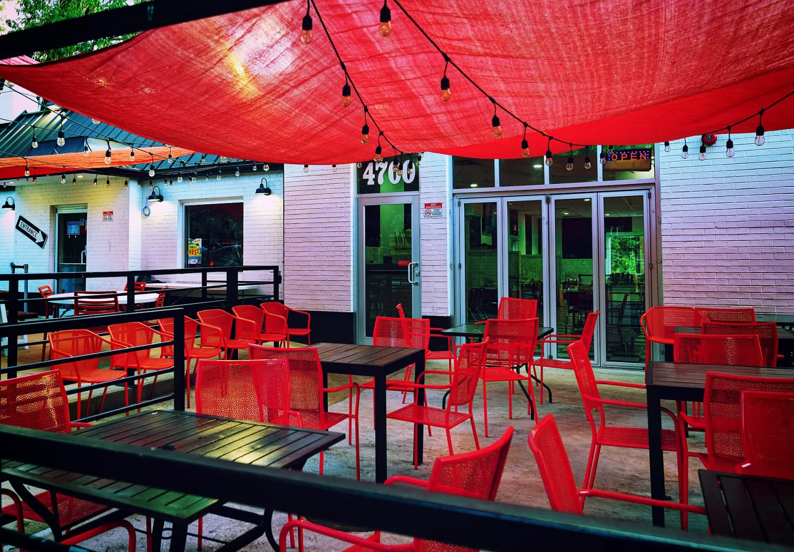 Tables and chairs on a restaurant patio under a shade sail. The photo was not taken in Clermont.